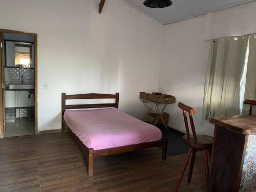 um pequeno quarto com uma cama e uma cadeira em Chalé da Ju em São Jorge