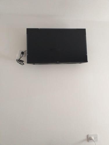 TV de pantalla plana en una pared blanca en Habitación independiente con baño privado en San Pedro