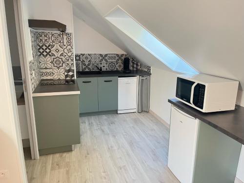 a kitchen with a microwave on a counter and a kitchen with a staircase at Le petit Saint Vincent, Neuf et calme in Lorcy