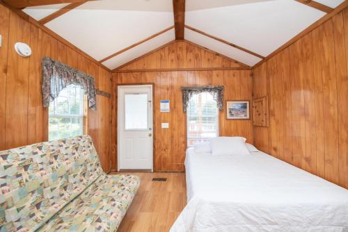 2 camas y un sofá en una habitación con paredes de madera. en Jellystone Park Waller en Waller