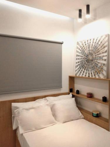 ein Schlafzimmer mit einem weißen Bett und einem Brett darüber in der Unterkunft Modi Stay in Thessaloniki