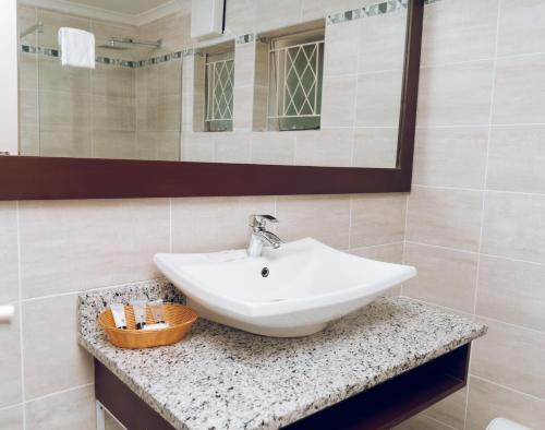 bagno con lavandino bianco e specchio di Great Zimbabwe Hotel a Nyanda