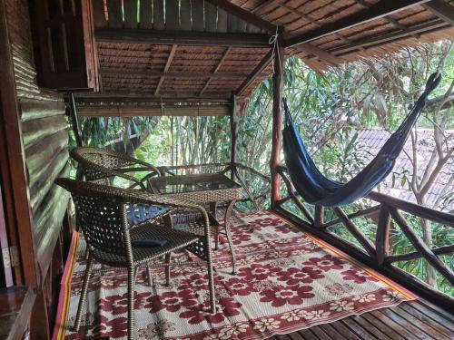a porch with a hammock and a table and chairs at Sabai Corner Bungalows - SHA Extra Plus in Ko Yao Noi