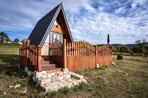 ein kleines Haus mit einem Holzzaun auf einem Feld in der Unterkunft A Pine vikendica u srcu Zapadne Srbije in Nova Varoš