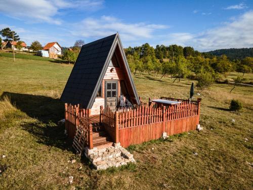 una pequeña casa con una valla en un campo en A Pine vikendica u srcu Zapadne Srbije en Nova Varoš