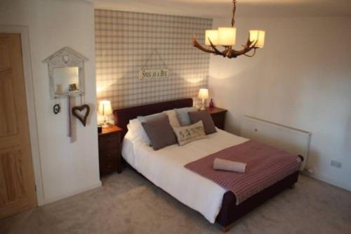una camera da letto con un letto grande e un lampadario di Upper Corronich a Boat of Garten