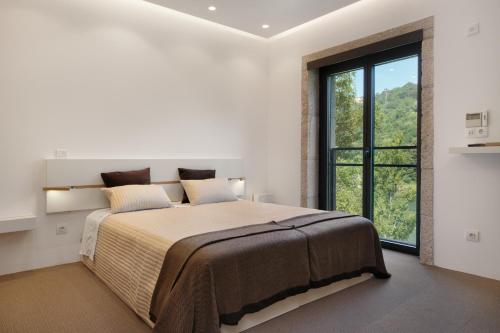 a bedroom with a large bed with a large window at Douro Green in Castelo de Paiva