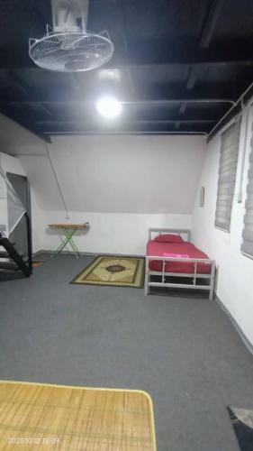 a room with a red bed and a table at Nour Homestay in Kaki Bukit