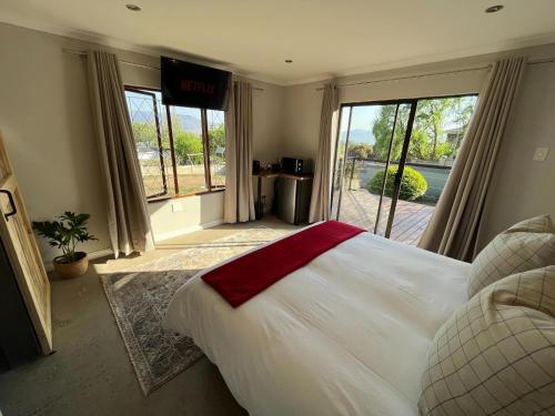 a bedroom with a large white bed and large windows at The Guesthouse Kokstad in Kokstad