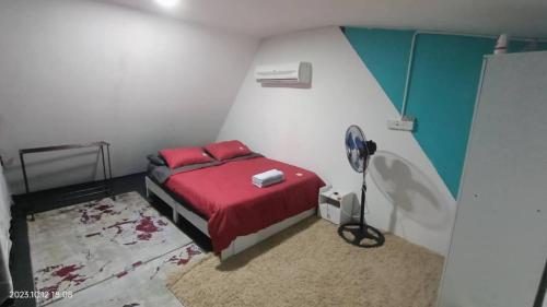 een slaapkamer met een bed met rode lakens en een ventilator bij Nour Homestay in Kaki Bukit