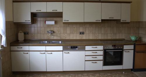 een keuken met witte kasten en een wastafel bij Fremdenzimmer Klinge in Haina