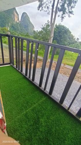 a fence with green grass next to a road at Nour Homestay in Kaki Bukit