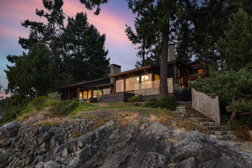 a house on a rocky hill with the lights on at Island Luxury Oceanside Estate in Saanichton