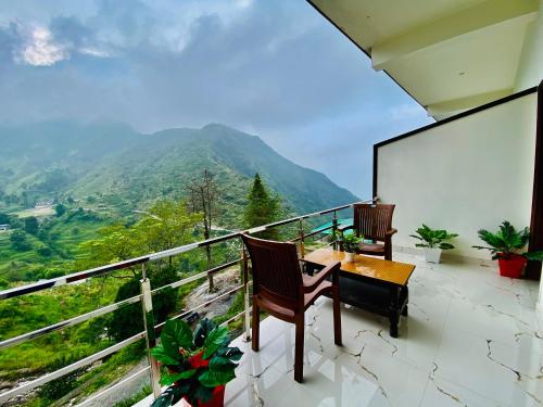 uma varanda com uma mesa e cadeiras e uma montanha em Hotel The SSB - Property of the Year ! Luxury Balcony Rooms ! Mountain View ! Rooftop Cafe ! Big Parking ! em Mussoorie