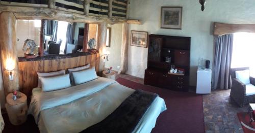 a bedroom with a large bed with a wooden headboard at TNiqua Stable Inn in Plettenberg Bay