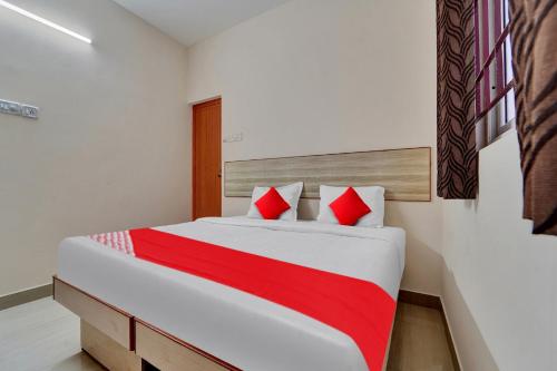 Pīlamedu的住宿－OYO Flagship Emerald Inn，一间卧室配有一张带红色枕头的大床