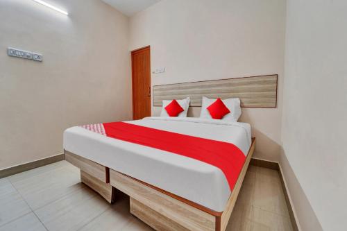a bedroom with a large bed with red pillows at OYO Flagship Emerald Inn in Pīlamedu