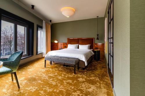 a bedroom with a bed and a chair and a window at Hotel Mai Amsterdam in Amsterdam