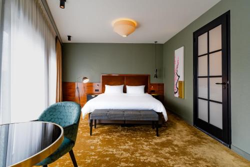 a bedroom with a bed and a glass table and chairs at Hotel Mai Amsterdam in Amsterdam