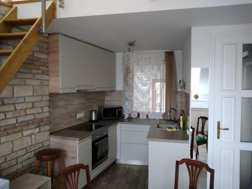 a kitchen with white cabinets and a brick wall at Kisfaludy Károly Apartman in Győr