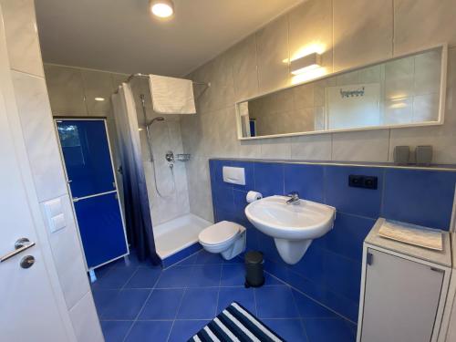 La salle de bains bleue est pourvue de toilettes et d'un lavabo. dans l'établissement Sonnenhang, à Sigmarszell