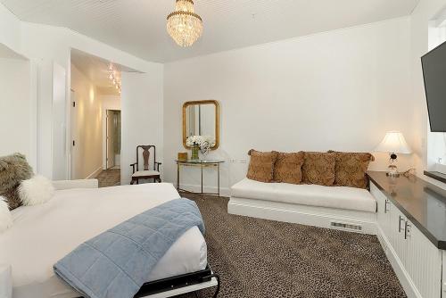 ein weißes Schlafzimmer mit einem Bett und einem Spiegel in der Unterkunft Independence Square 310, Chic, Remodeled Studio w/ Great Location in Aspen, A/C, & Kitchenette in Aspen