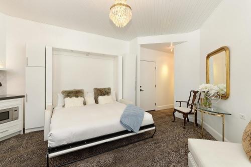 a white bedroom with a bed and a mirror at Independence Square 310, Chic, Remodeled Studio w/ Great Location in Aspen, A/C, & Kitchenette in Aspen