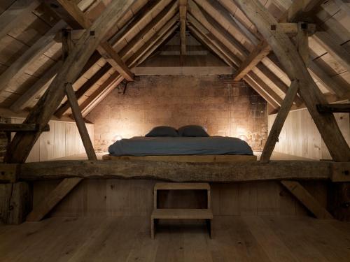 ein Bett auf dem Dachboden eines Holzgebäudes in der Unterkunft Hoeve Appartement aan de rand van Maastricht met natuurzwembad in Berg en Terblijt