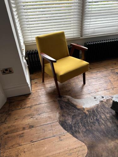 a yellow chair sitting on top of a wooden floor at Quirky spacious ground floor Victorian garden flat in Worthing