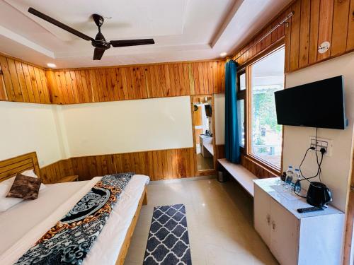 a room with two beds and a flat screen tv at The Stream Kasol in Kasol