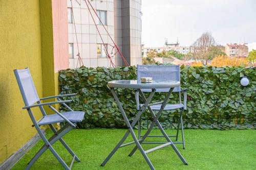 a table and two chairs on a patio with grass at Occidental Wise Transit in Bucharest