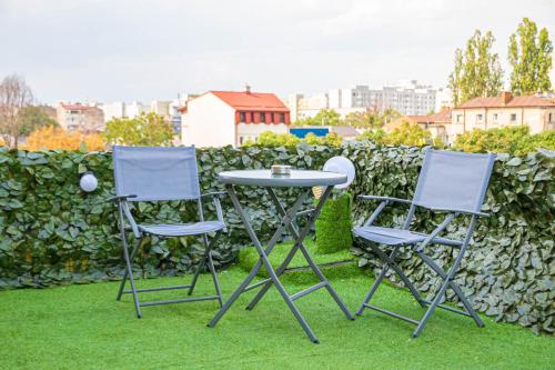 three chairs and a table in the grass at Occidental Wise Transit in Bucharest