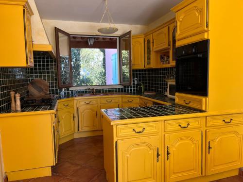 une cuisine jaune avec des armoires jaunes et une fenêtre dans l'établissement Villa du Cap de 5 chambres et sa grande piscine, au Cap d'Agde