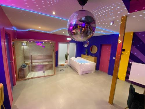 um quarto roxo com uma banheira e uma bola de discoteca em Capsule Boogie-Woogie - JACUZZI - SAUNA - BILLARD - JEUX - ECRAN GÉANT - FILET SUSPENDU - NETFLIX em La Louvière