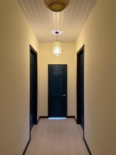 un couloir vide avec deux portes noires et un plafond dans l'établissement Tranquera House, à Ranau