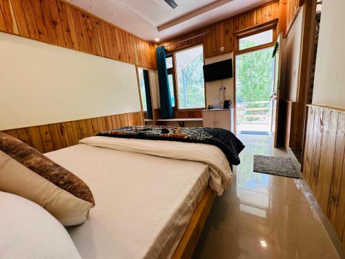 a bedroom with two beds and a large window at The Stream Kasol in Kasol