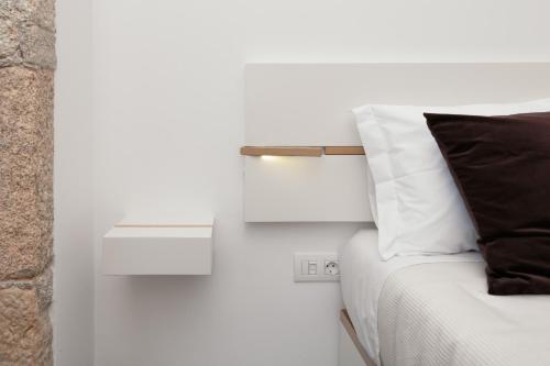 a white bed with a black pillow and a side table at Douro Green in Castelo de Paiva