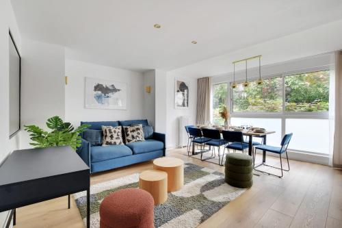 een woonkamer met een blauwe bank en een tafel bij Chic 3-Bedroom Parisian Apartment in Vibrant Vincennes in Parijs