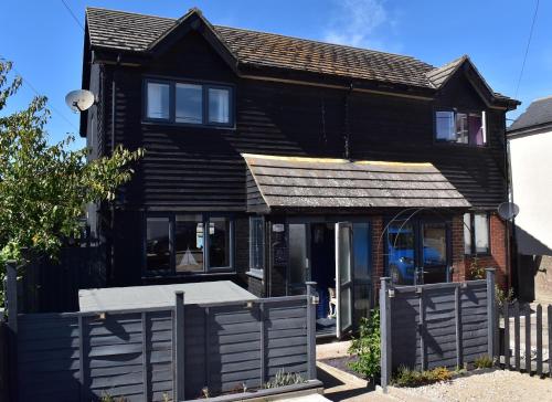 a black house with a fence in front of it at Snaffles a family friendly holiday cottage in Rye Harbour