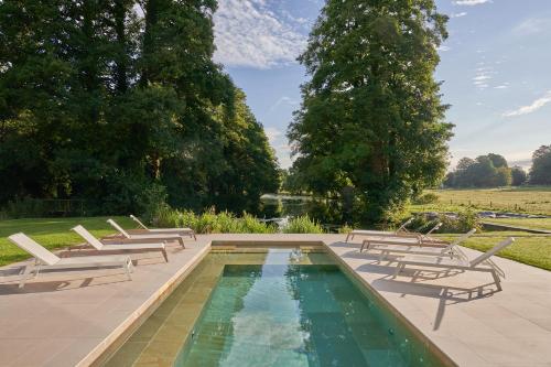 a swimming pool with lounge chairs and a pond at Avington Estate in Winchester