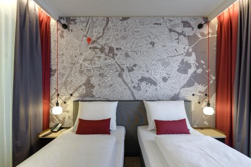 two beds in a room with a map on the wall at IntercityHotel Herford in Herford