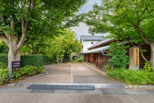 une rue vide avec des arbres et un bâtiment dans l'établissement ゲストハウス小布施, à Obuse