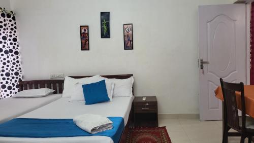 a bedroom with a bed with blue and white pillows at LA CASA THE HOMESTAY in Trivandrum