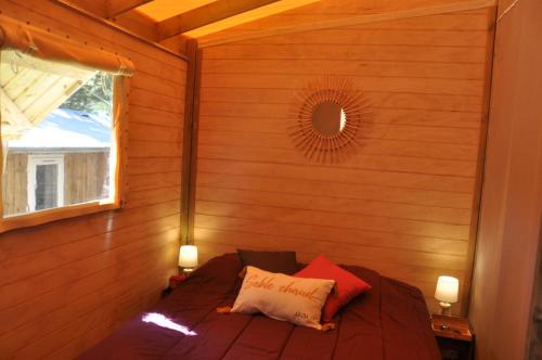 een kleine kamer met een bed in een houten muur bij Flower Camping Les Biches in Saint-Hilaire-de-Riez