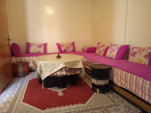 Cette chambre comprend deux lits, une table et un canapé. dans l'établissement Rez-de-chaussée villa touta, à Béni Mellal