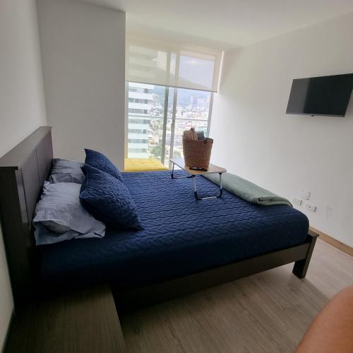 a bedroom with a bed with blue sheets and a window at Suite Martina 2 Personas Quito in Quito