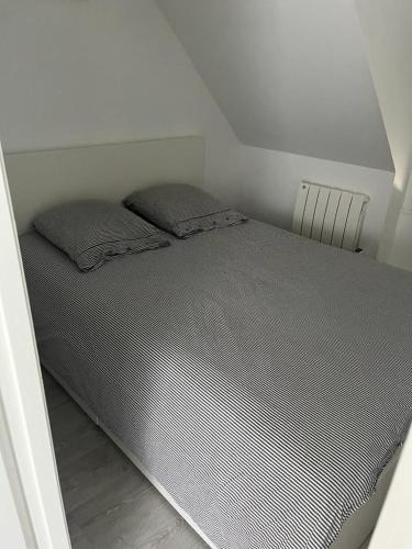 ein Bett mit zwei Kissen auf einem Zimmer in der Unterkunft KERVILLEN in La Trinité-sur-Mer