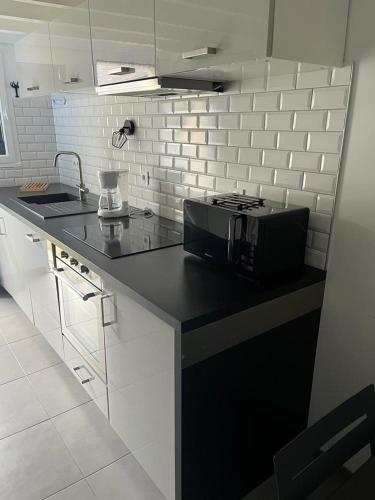 eine Küche mit einer schwarzen Arbeitsplatte und einer Mikrowelle in der Unterkunft KERVILLEN in La Trinité-sur-Mer