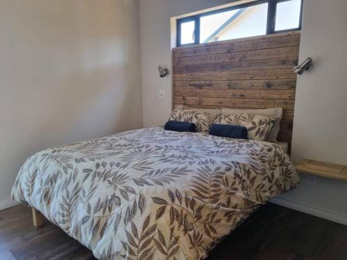 a bedroom with a large bed with a wooden headboard at Brand new cottage, walk to beach - inverter, wi-fi, DSTV in Cape St Francis