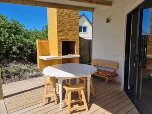 a patio with a white table and chairs on a deck at Brand new cottage, walk to beach - inverter, wi-fi, DSTV in Cape St Francis